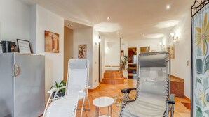 A hotel lobby with a reception desk, two lounge chairs, a refrigerator, and a staircase leading to an upper floor. - Apartment with wellness oasis (Hellenthal- Reifferscheid)
