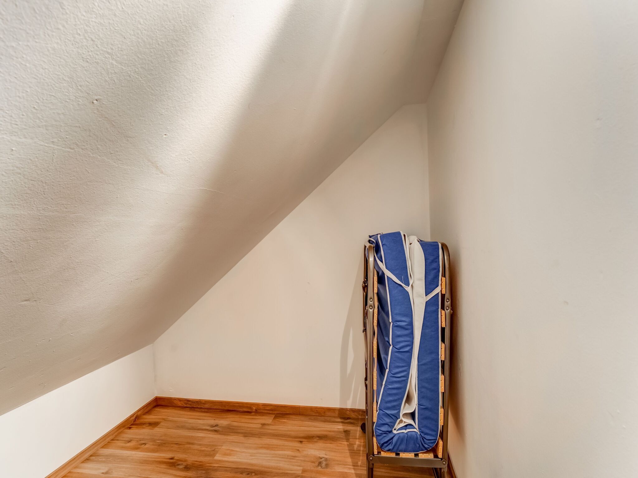 Un coin de pièce avec un plancher en bois et des murs blancs.