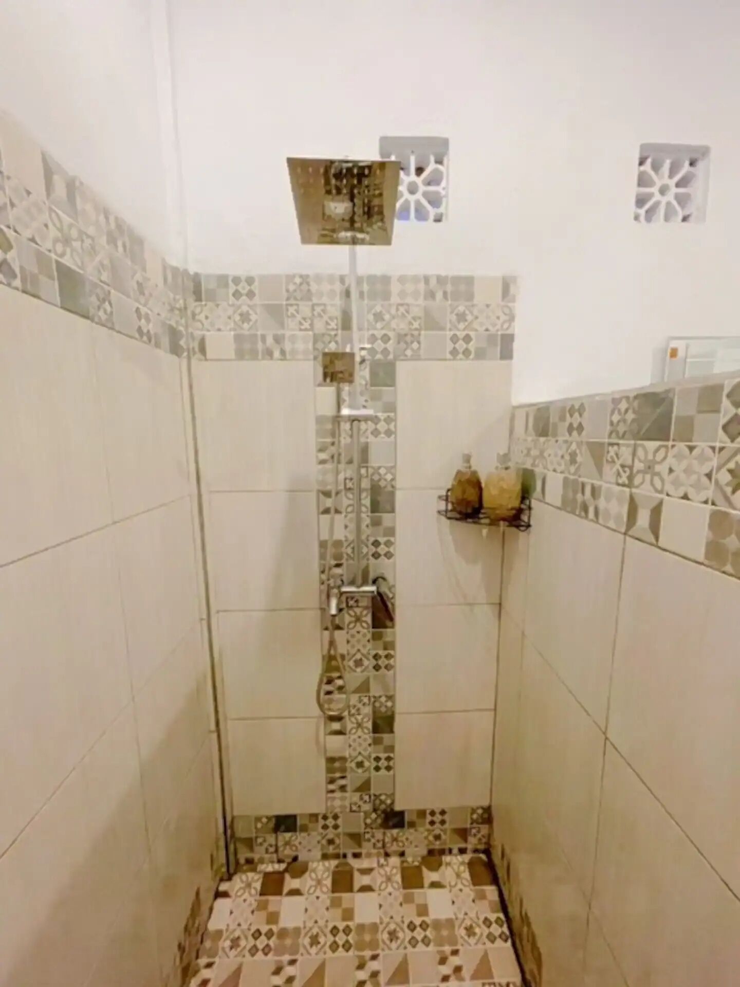 A shower with patterned tiles and a metal showerhead.