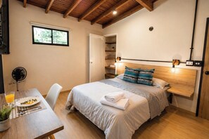 A bedroom with a bed, bedside table, and a window.