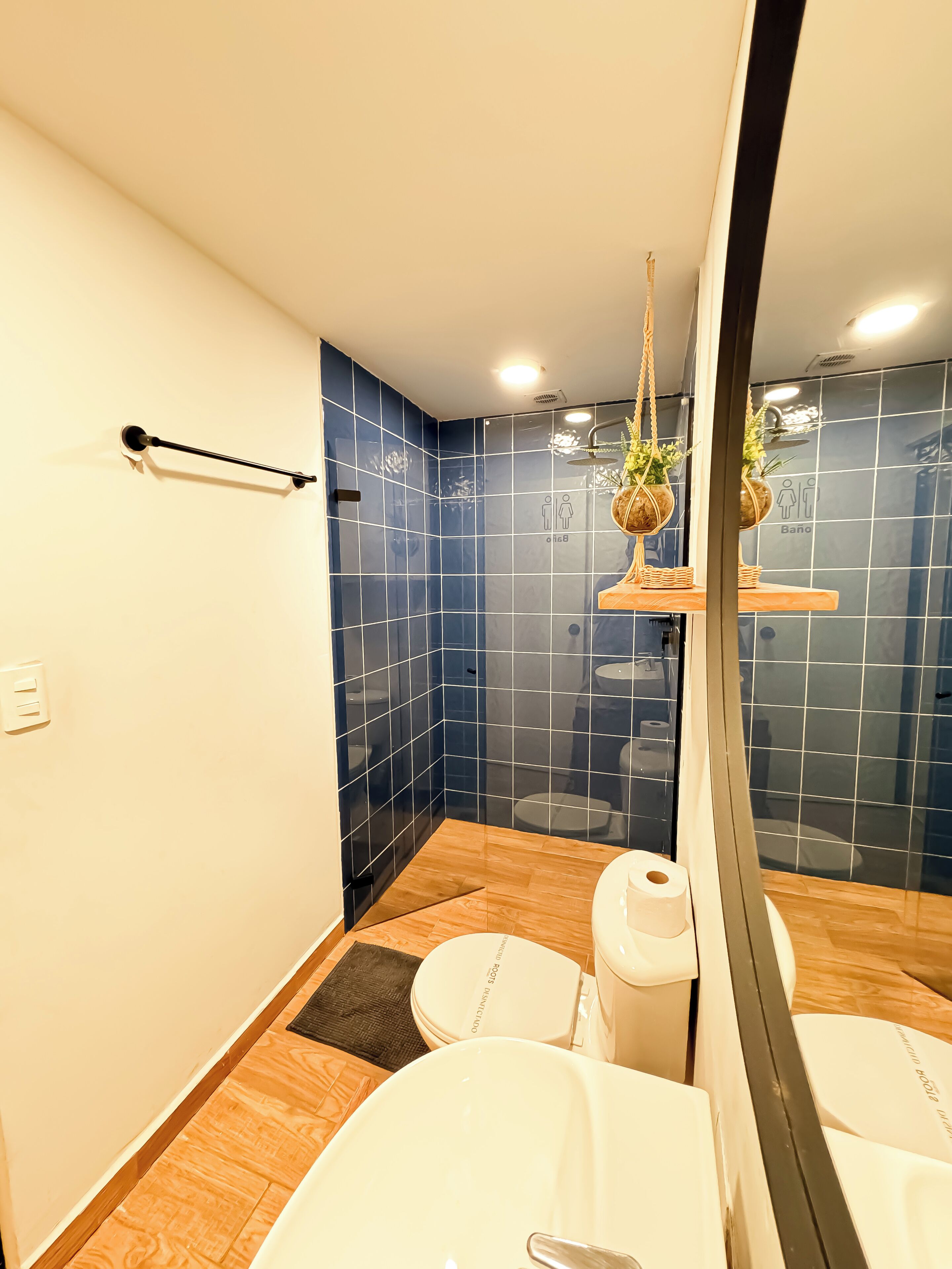 Un baño moderno con un espejo grande, accesorios blancos y paredes con azulejos azules.