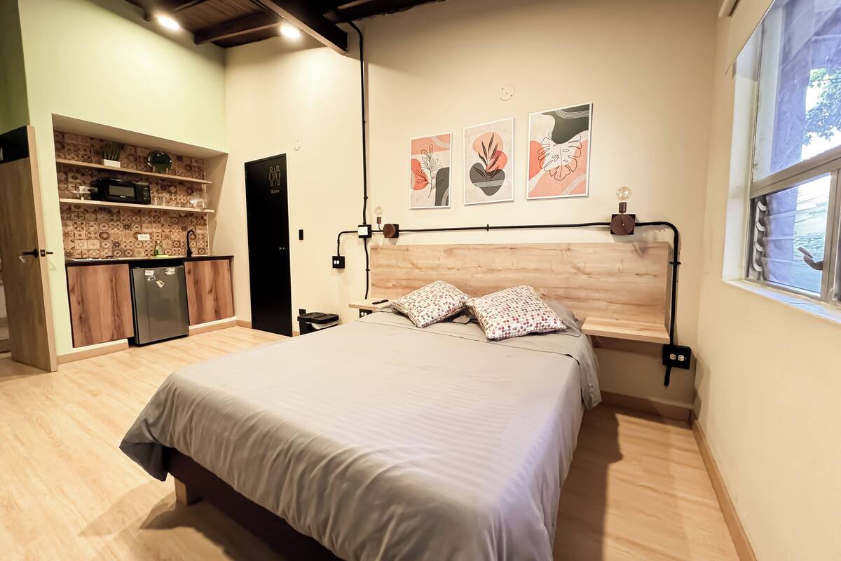 Une chambre avec un lit, un bureau intégré, une petite kitchenette et une fenêtre donnant sur un beau paysage.