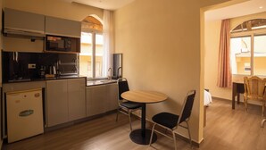 A compact kitchen with a microwave, sink, and a small refrigerator. There is a dining area with a round table and two chairs. - Aparthotel Madeleine (Antananarivo)