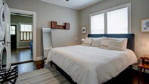 Une chambre avec un grand lit, un ventilateur de plafond, un lave-linge et une vue sur un balcon.