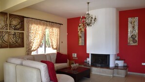 A living room with a sectional sofa, a fireplace, and a chandelier. - The Brilliant Villa Pernera (Pernera)
