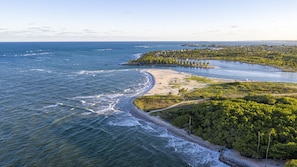 Vista aérea de una zona costera con playa, una península boscosa y una vista despejada del océano.