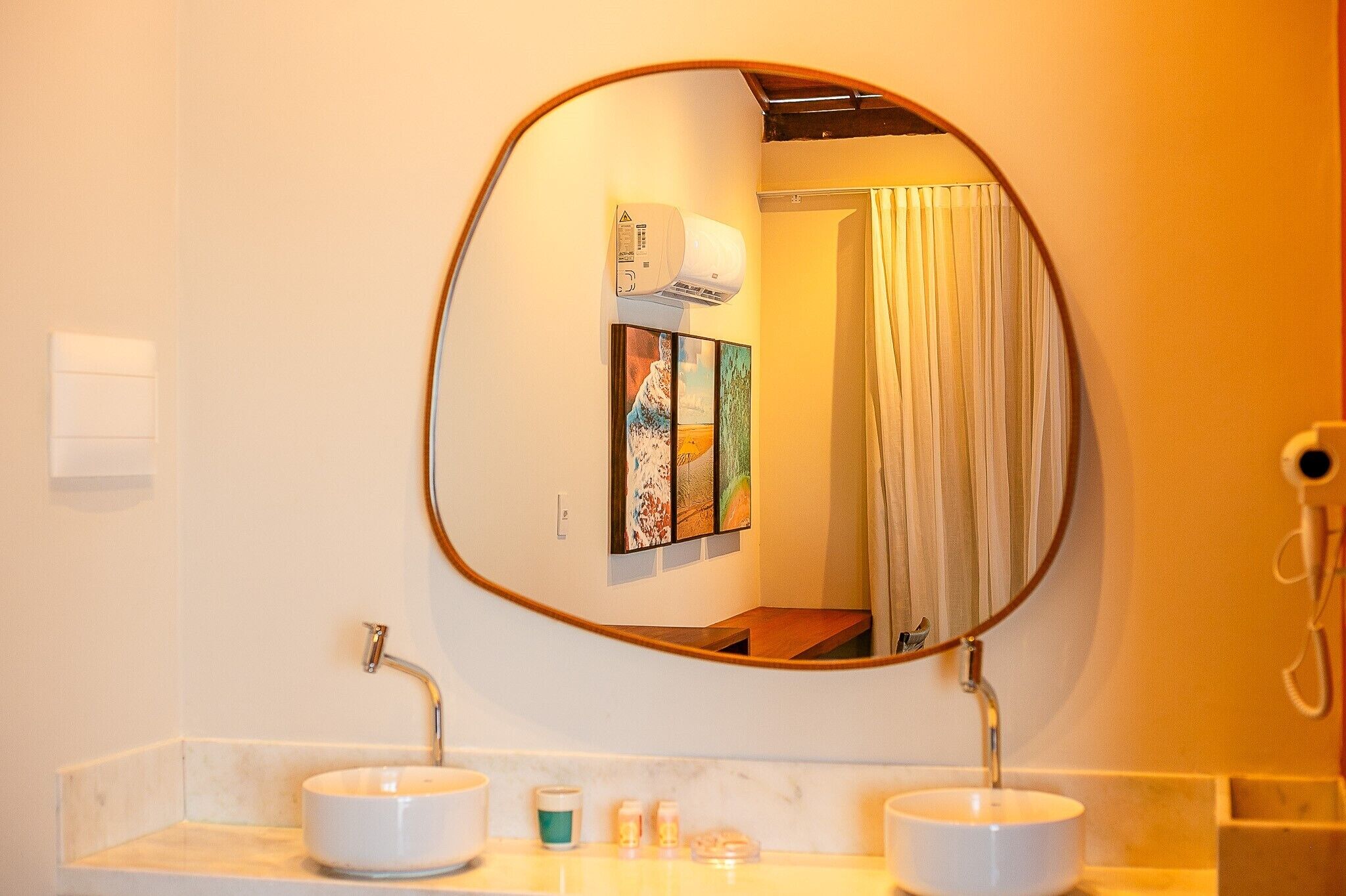 A bathroom with a round mirror, two sinks, and a towel rack.