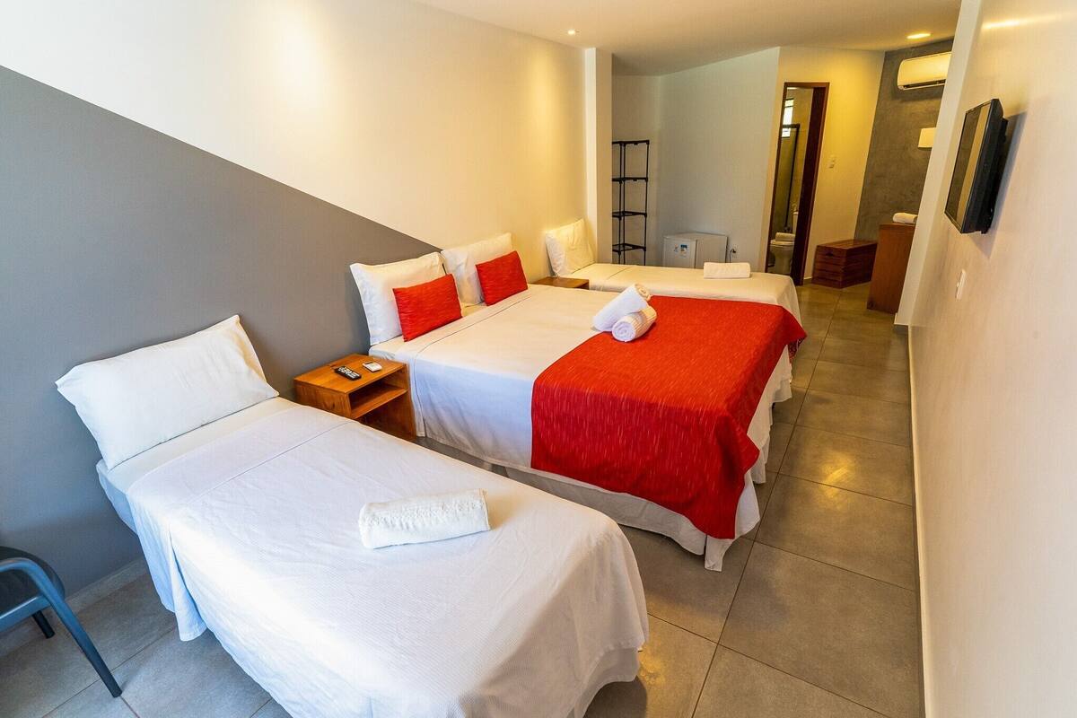 A hotel room with two beds, a small table, a chair, and a mirror.