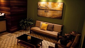 A cozy lounge area with a sofa, a small table, and a wall-mounted painting. - Un Paso Del Mar (Ipojuca)