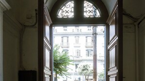 Un arco de entrada que da a una calle con peatones y una scooter estacionada.