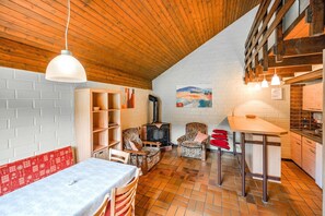 Un interior acogedor con techo de madera, pared de ladrillo, chimenea y zona de comedor.