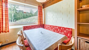 A cozy room with a table and chairs, a window with curtains, a brick wall, and a hanging light fixture. - Ferienhaus mit herrlicher Aussicht (Bestwig-Untervalme)
