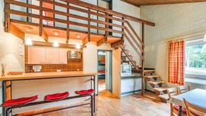 A kitchen with a wooden staircase, a dining area with a table and chairs, and a view of the outdoors through a window. - Ferienhaus mit herrlicher Aussicht (Bestwig-Untervalme)