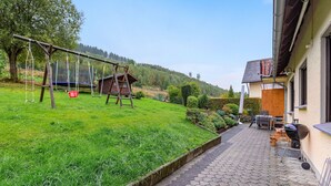 A patio with a grill, outdoor seating, and a swing set. - Apartment with private terrace in Velmede (Bestwig-Velmede)
