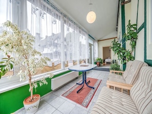 A room with a large window, a round table, a sofa, and various plants. - Madfeld Apartment Retreat (Brilon-Wald)