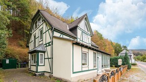 A traditional half-timbered house with a paved driveway and a wooden fence with decorative metalwork. - Madfeld Apartment Retreat (Brilon-Wald)