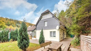 A house with a sloped roof, a satellite dish, and a paved patio with wooden benches. - Madfeld Apartment Retreat (Brilon-Wald)