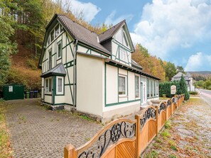 A traditional half-timbered house with a paved driveway and a wooden fence with decorative metalwork. - Madfeld Apartment Retreat (Brilon-Wald)