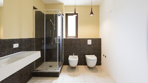 Une salle de bain moderne avec une douche à parois de verre, un lavabo blanc et des toilettes.