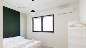 Une chambre d’hôtel avec un lit, une fenêtre, un appareil de climatisation et une armoire blanche.