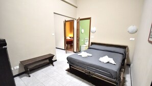 Een slaapkamer met een bed, een bankje en een deur die naar een andere kamer leidt.