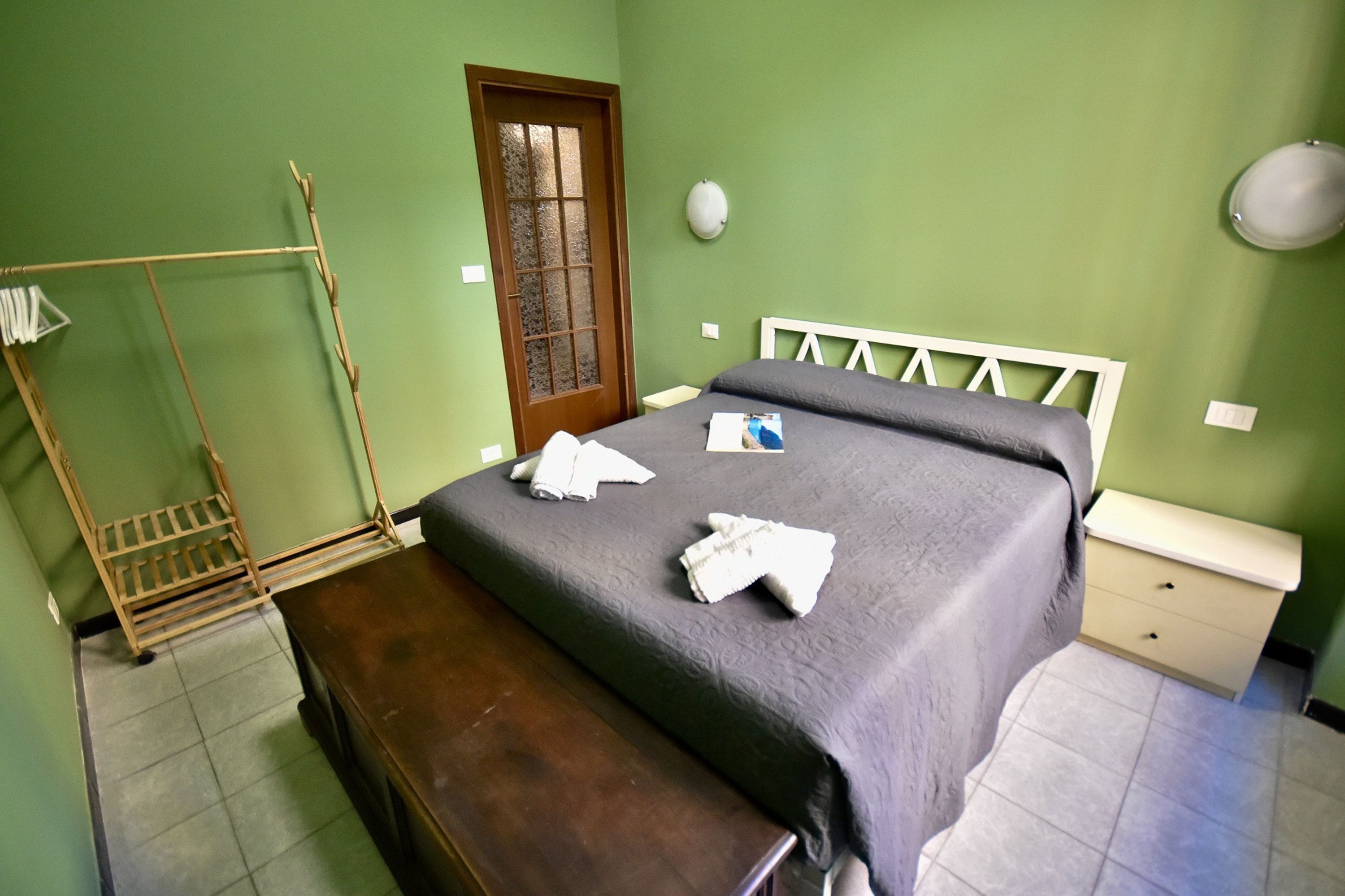 A room with a bed, a wooden bench, a wardrobe, and a door.
