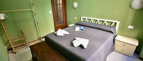 A room with a bed, a wooden bench, a wardrobe, and a door.