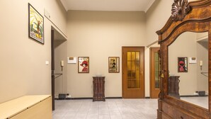 Een gang met een houten dressoir, een spiegel en kunstwerken in lijsten aan de wanden.