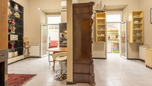 Een ruime woonkamer met een grote houten kolom, een eethoek met tafel en stoelen, en een keuken met open kasten.