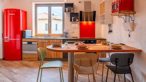 Una cocina moderna con un refrigerador rojo, armarios de madera y un comedor con sillas.
