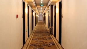 A hotel hallway with carpeted floors and doors on both sides. - Fubainian Business Hotel (Qingdao)