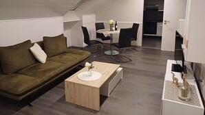 Moderni olohuone, jossa on sohva, sohvapöytä ja ruokailutila.