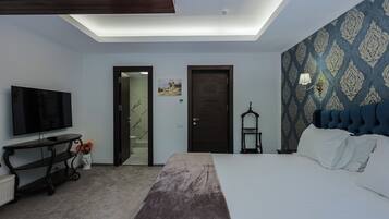 Habitación de hotel con cama, televisión, escritorio, silla y pared con diseño.