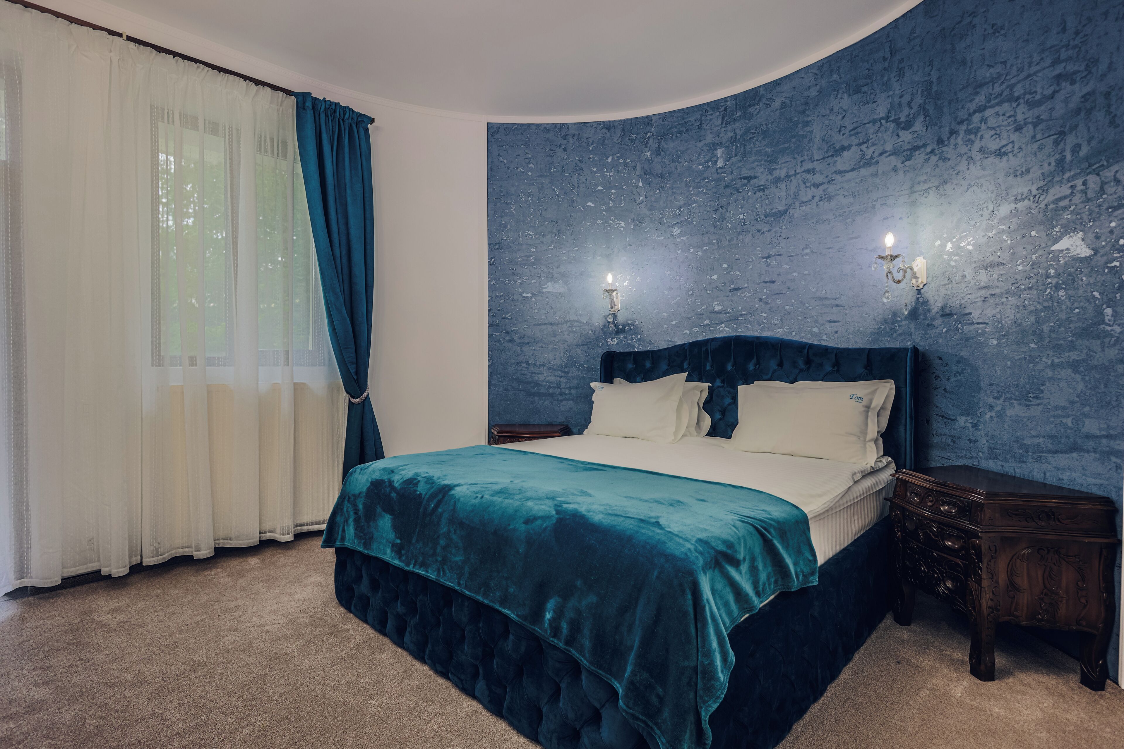 Ein Schlafzimmer mit einem großen Bett, einem Nachttisch und zwei Wandleuchten.
