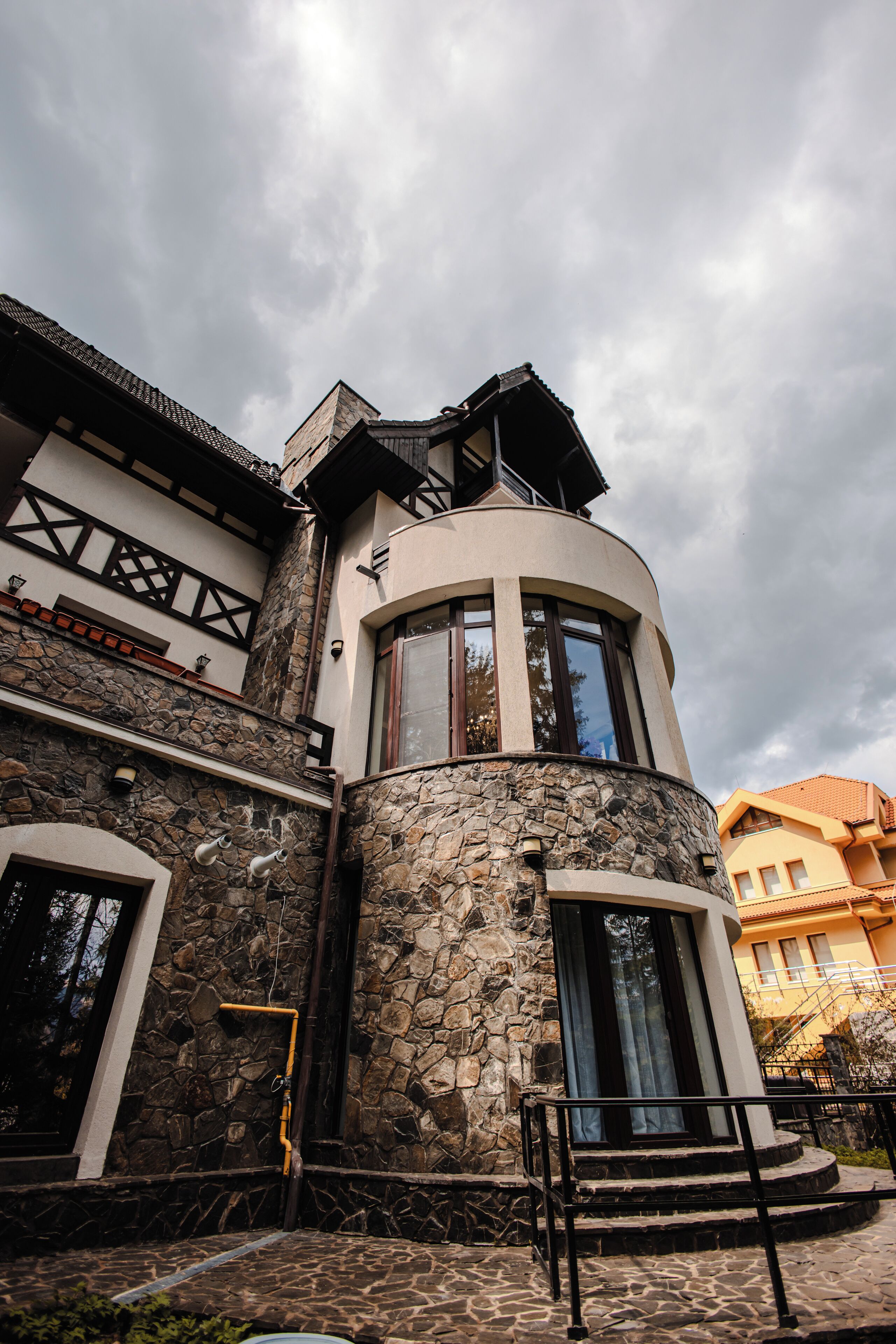 A building with a stone facade, a curved corner entrance, and a balcony.