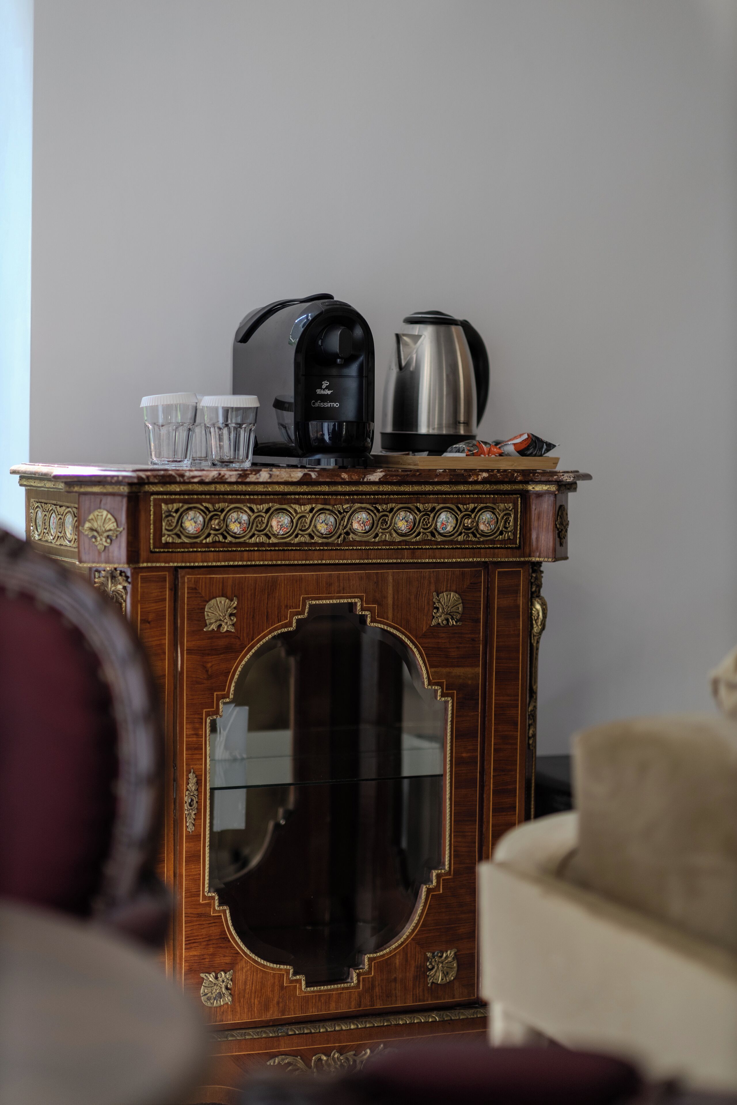 Un mueble de madera con un espejo, una cafetera y dos tazas.