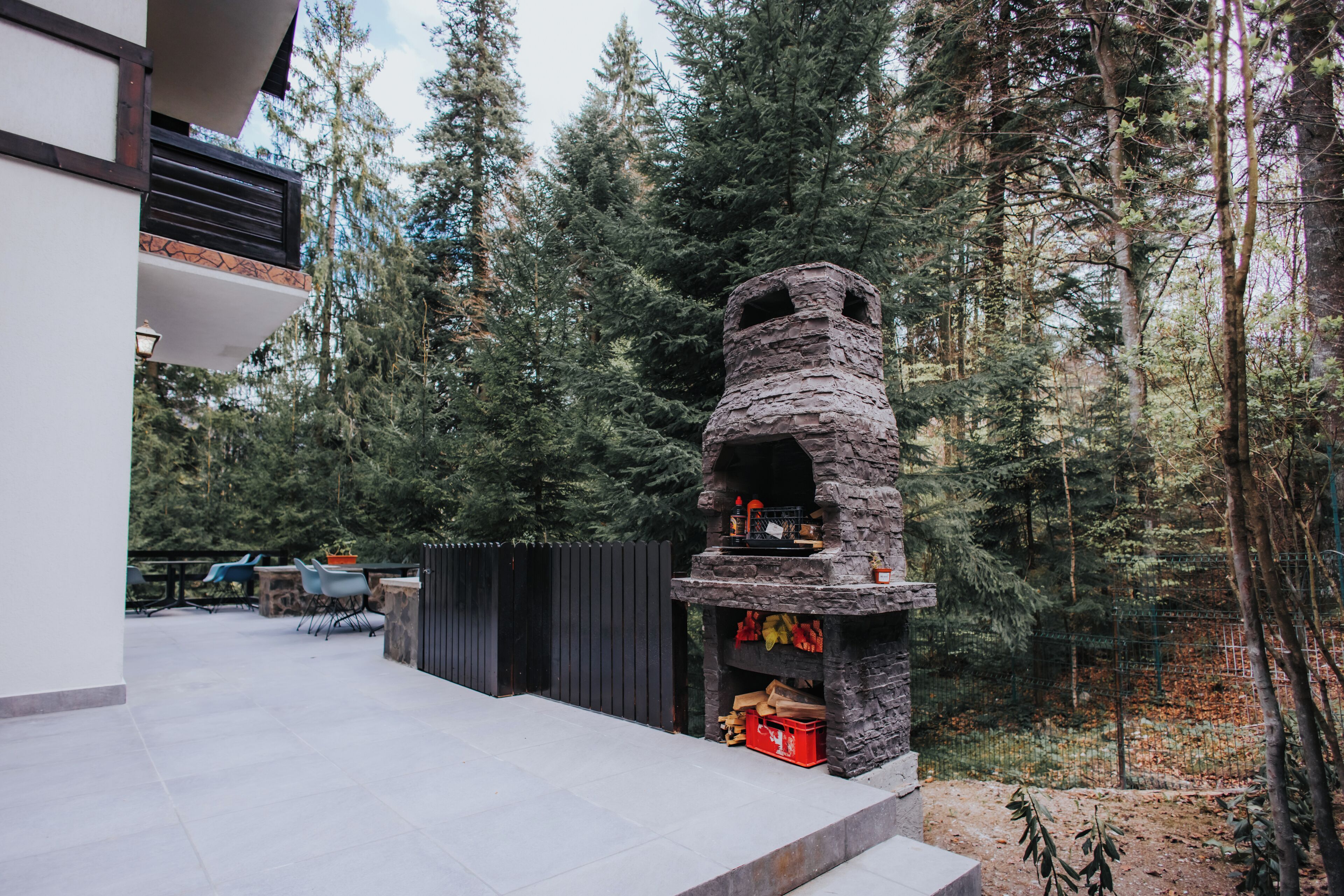 A stone-built outdoor oven with a chimney, surrounded by a forested area.