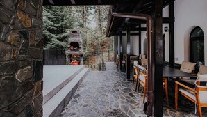 A stone-tiled patio with outdoor seating and a stone fireplace.