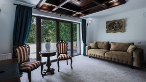 A room with a large window, a sofa, two striped chairs, and a small table.