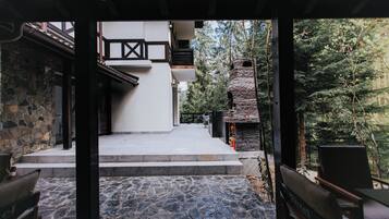 A stone pathway leading to a building with a stone facade and a wooden deck.