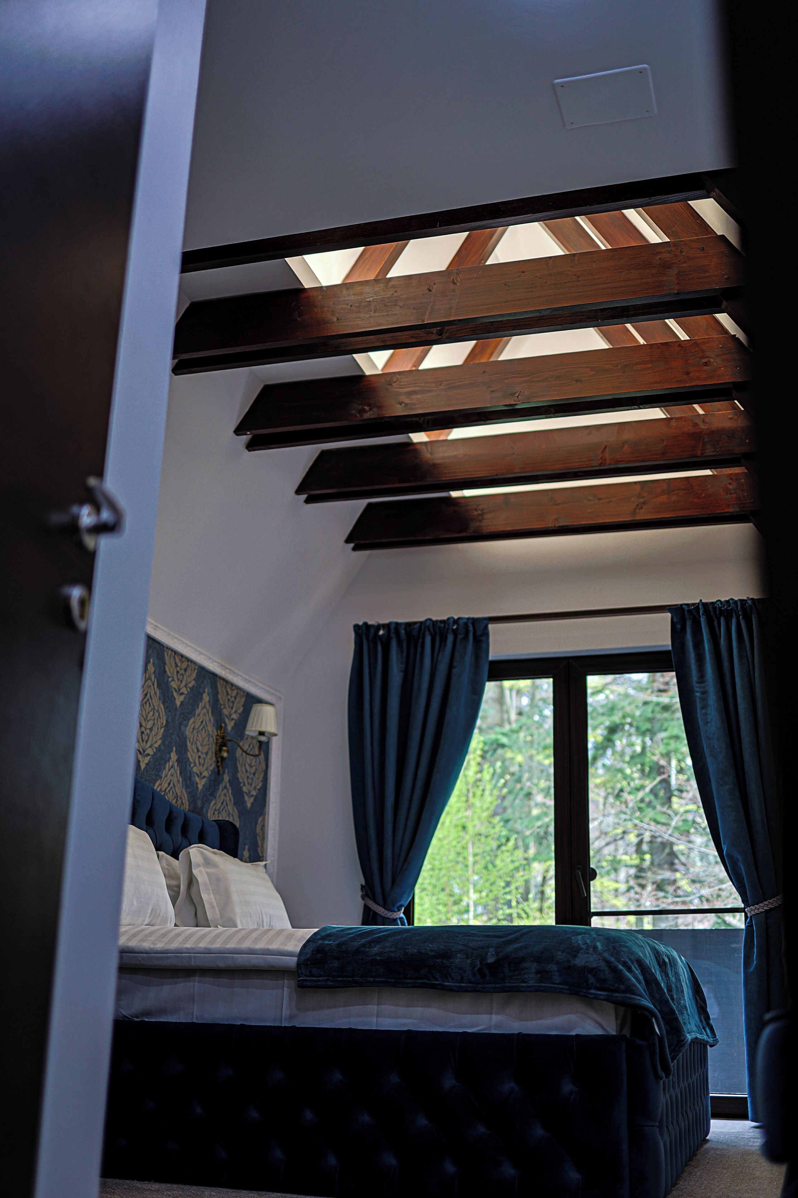 Une chambre à coucher avec un lit, une fenêtre avec des rideaux et une lucarne.