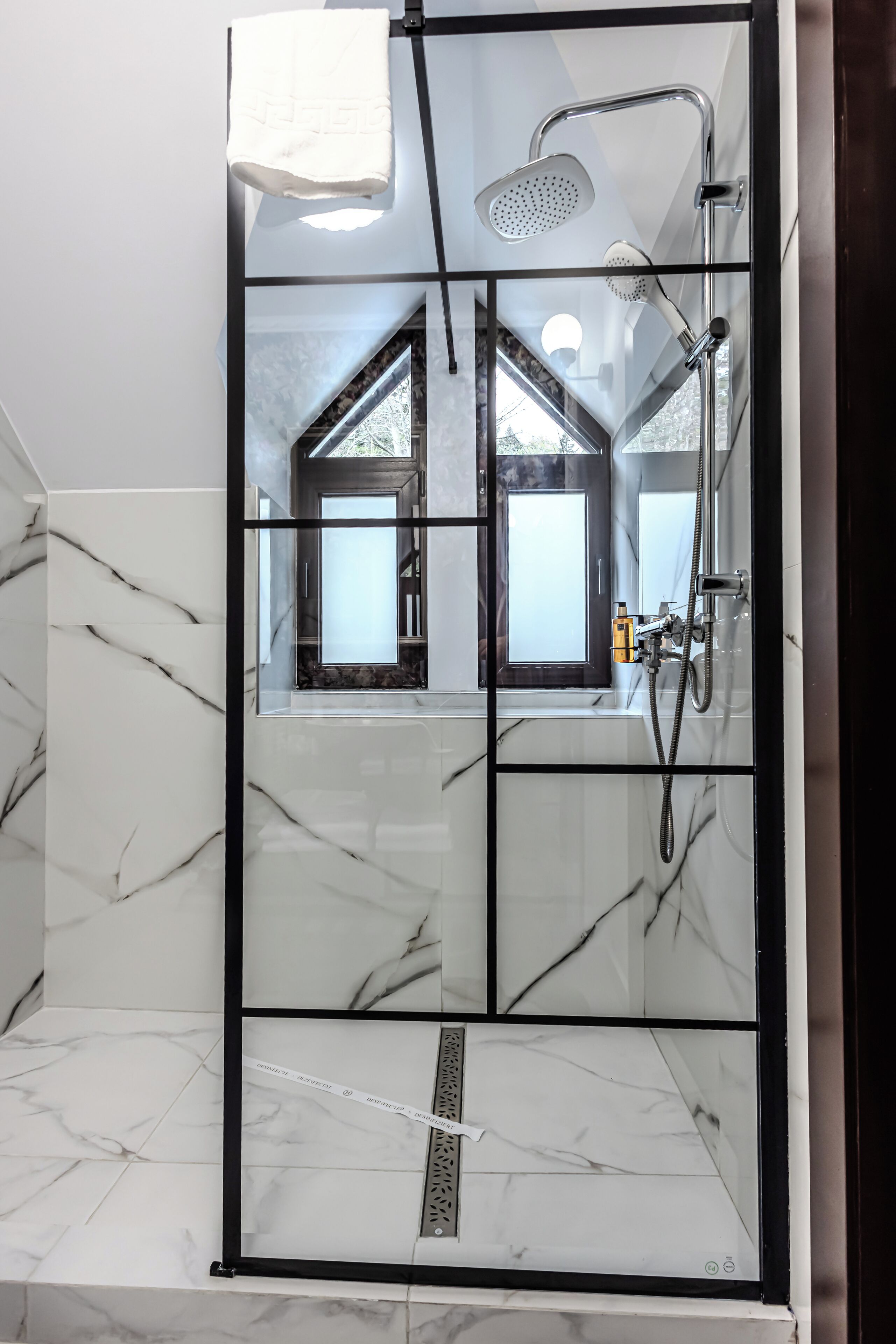 Un baño moderno con cabina de ducha de vidrio, un espejo grande y vistas al exterior.