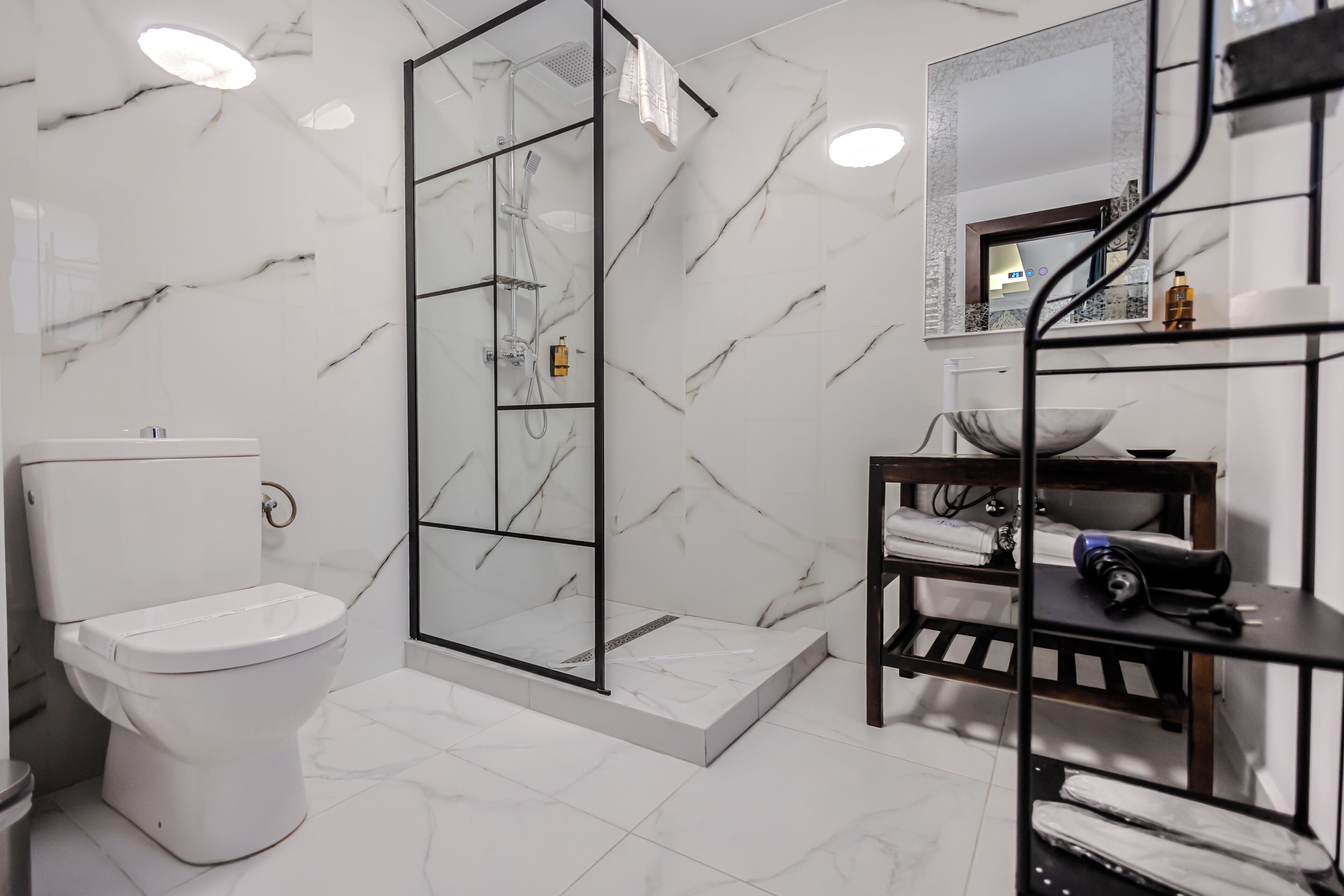 Een moderne badkamer met toilet, douche en marmeren wanden.