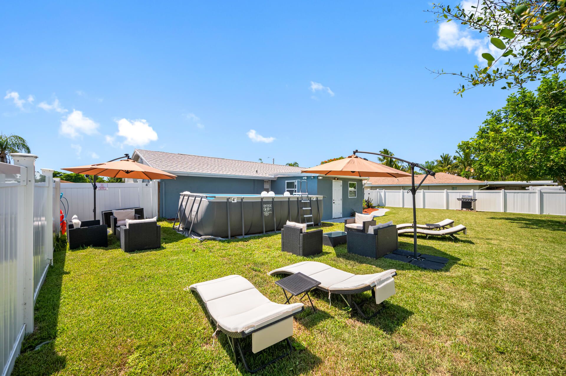 Un jardin avec une piscine, des chaises longues et un patio couvert.
