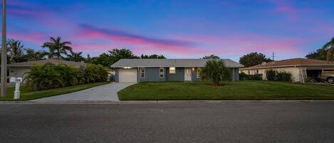 Une maison de plain-pied avec un garage, une pelouse bien entretenue et une vue sur la rue.