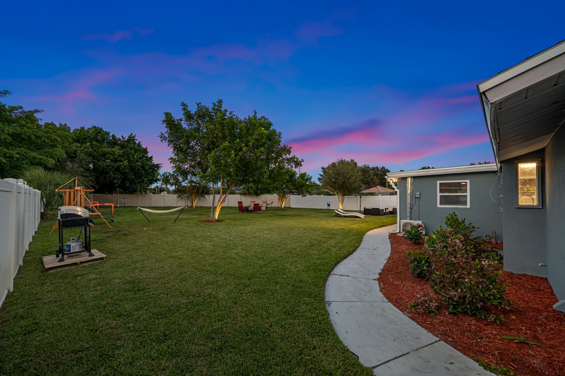 A backyard with a well-maintained lawn, a hammock, and a playset.