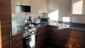 A modern kitchen with wooden cabinets, a stainless steel oven, a microwave, a kettle, and a toaster. - Tranquil, pet friendly apartment In Norwich city centre (Norwich)