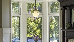 A corner seating area with a table and bench, large windows with a view of trees, and a fireplace.