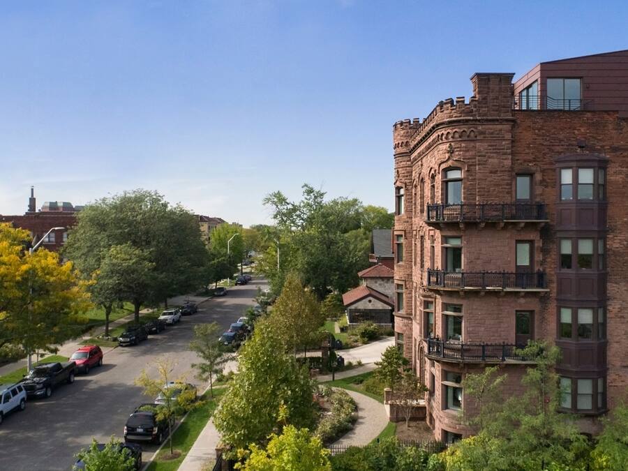 A multi-story brick building with a central courtyard, surrounded by trees and parked cars.