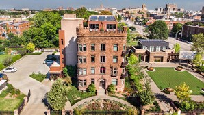 A multi-story building with a brick facade, large windows, and a solar panel on the roof.